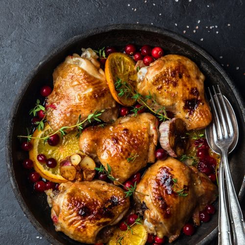 roasted  chicken with orange, cranberry and spicy herbs on pan , black concrete background, copy space, top view,